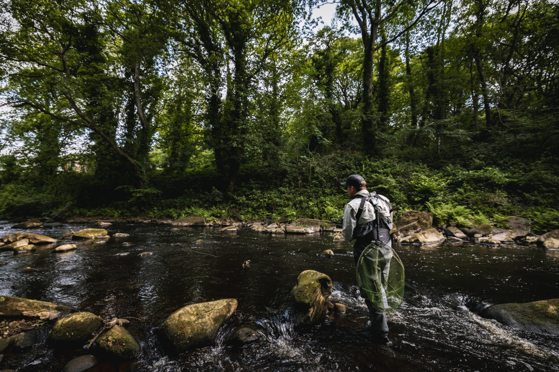 James cast his line along the rocks in encourage the fish out of hiding